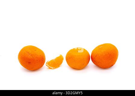 Three bright, whole mandarins are arranged in a row with one peeled segment in the center. An isolated object on a clean white background. Stock Photo