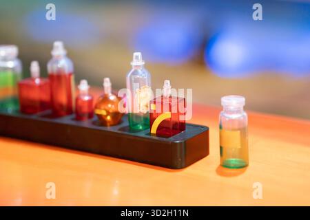 A row of small glass bottles filled with bright liquids sits on a black plastic rack, creating a vibrant laboratory scene perfect for science, chemistry, and education visuals. High quality photo Stock Photo
