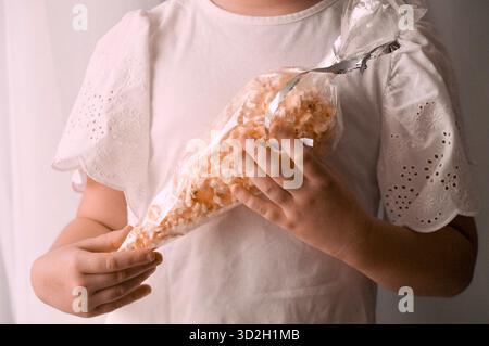 A child in a white T-shirt is eating a cookie. Stock Photo