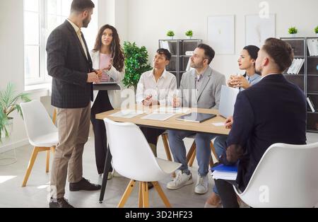 Gathering for meeting in modern office, diverse group of colleagues sitting listening, talking  Stock Photo