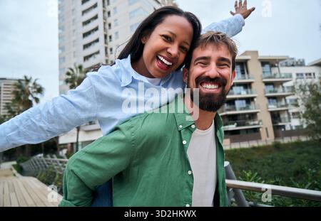 Interracial couple piggybacking and having fun in the city Stock Photo