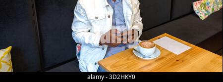 Banner of anonymous black man chatting with his phone alone in cafe. Social media addiction concept Stock Photo