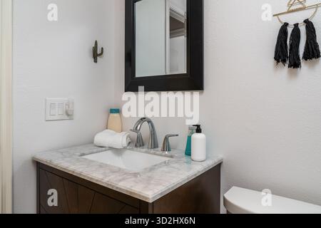 White modern bathroom interior with marble sink, faucet, mirror, towel, soap, lotion, wall hook Stock Photo