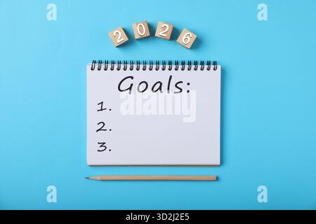 New 2026 Year Goals. Inscription in notebook and cubes with numbers on light blue background, top view Stock Photo