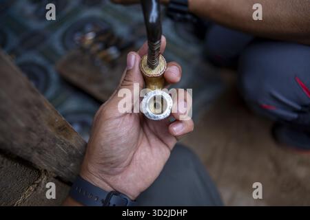 Close up of focused man hand working on metal pipe. diligent plumber using tool for plumbing repair on brass valve in workshop, showing industrial ski Stock Photo