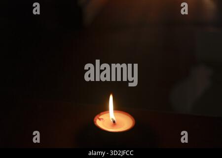 Single burning candle light creates peaceful, warm flame in dark. spiritual symbol of hope and fire glowing against black background offering serene c Stock Photo