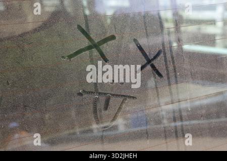 Simple, sad, tired, funny drawing of dead emoticon on dusty window. This simple doodle expresses feeling of complete exhaustion and dizziness on dirty Stock Photo