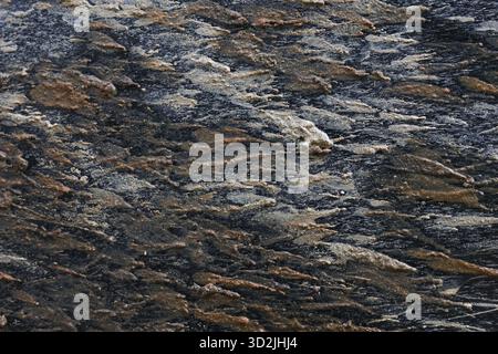 Rugged close up of natural stone texture background. This abstract pattern with gray, brown, and black tones shows detail of geology and rough materia Stock Photo