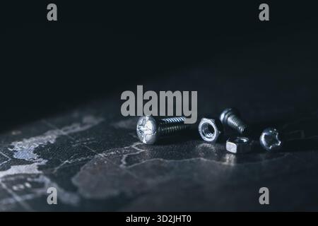 Close up of metal nut, bolt, and screw on dark industrial background. Concept of repair, construction, and hardware with dramatic lighting and copy sp Stock Photo