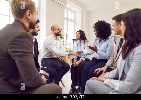 Multicultural group of happy business people sitting on chairs in a circle Stock Photo
