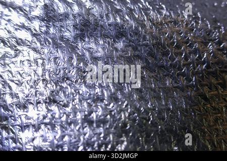 Shiny silver foil background with crinkled, metallic texture. An abstract, reflective surface, close up of insulation material showing bumpy and uneve Stock Photo