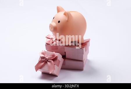 Piggy bank on stack of gift boxes. White background Stock Photo