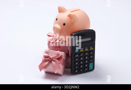 Piggy bank on stack of gift boxes and calculator. White background Stock Photo