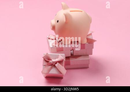 Piggy bank on stack of gift boxes. Pink pastel  background Stock Photo