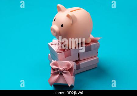Piggy bank on stack of gift boxes. Blue  background Stock Photo