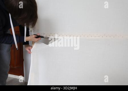 Man cutting tufting cloth from wooden frame after handmade rug making Stock Photo