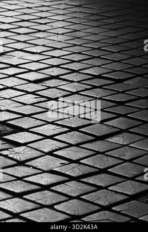 Black and white photo of wooden pavement blocks forming a repeating geometric pattern. Stock Photo