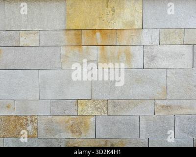 Natural stone facade with smooth slabs and yellowish-brown discoloration. Close-up. Copyspace. Stock Photo