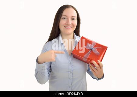 smiling woman holding a present and pointing it with her finger  on a white background Stock Photo