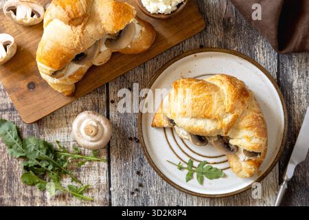 Freshly baked croissants with mushrooms and ricotta on rustic wooden table setting. Top view flat lay background. Stock Photo