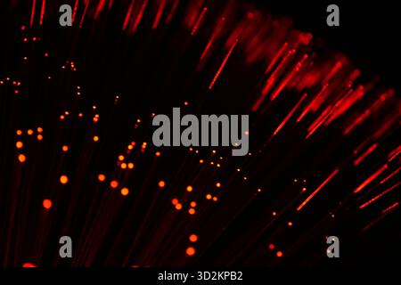 An abstract close-up of vibrant red fiber optic strands, suggesting data transmission and futuristic technology on a dark background. Stock Photo
