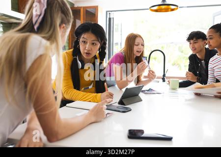 Teens collaborating on school project at home, using tablet and taking notes. Collaboration, teamwork, studying, digital device, creativity, brainstorming || Model released Stock Photo