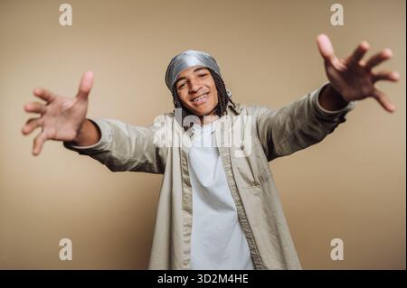 Young man with outstretched arms, smiling, wearing a headscarf. Stock Photo