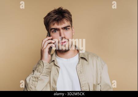 Young man with a surprised expression talking on a smartphone. Stock Photo