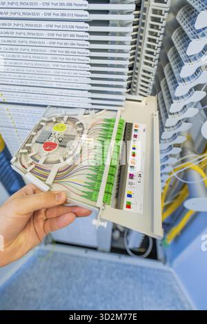 Hand holding a fiber optic cabling module in a technical environment, optical fiber Stock Photo