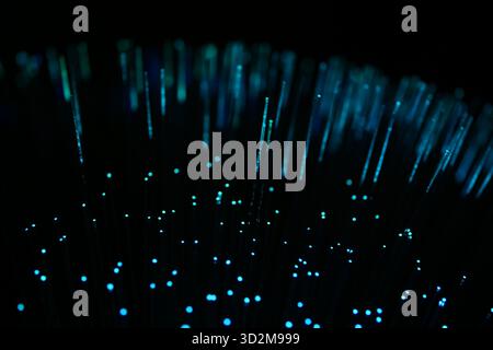 Abstract close-up of vertical, intensely blue fiber optic strands on a dark background, suggesting data and high-tech connection. Stock Photo