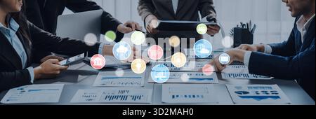 A diverse business team engages in a collaborative meeting, analyzing data and discussing strategies as digital icons illustrate key concepts for inno Stock Photo