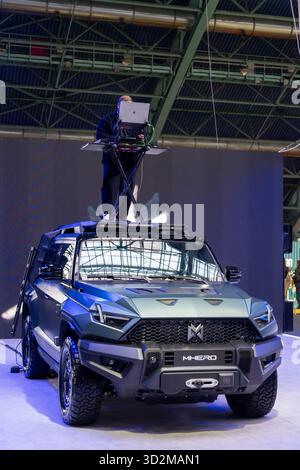 MINSK, BELARUS - JUNE 3, 2025: A DJ plays music from a control panel on the roof of a Dongfeng M-Hero SUV at an indoor auto show, creating a festive a Stock Photo