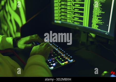 Hacker in hoodie working hacks code site on personal computer. War and cyber attack spy concept Stock Photo