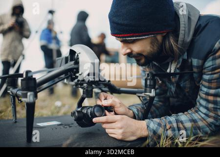 Man pilot checking quadcopter drone camera before aerial flight and filming Stock Photo