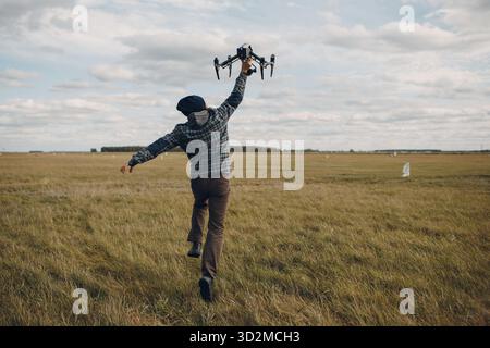 Man pilot holding quadcopter drone in hands at outside field Stock Photo
