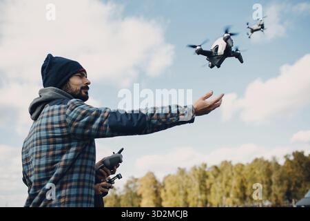 Man pilot Launches quadcopter drone from hand to sky flight Stock Photo