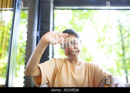 Headshot of indian woman sit on potdoor cafe waving hand looks to camera make video call chat use computer laptop webcam view, vlogger record webinar Stock Photo