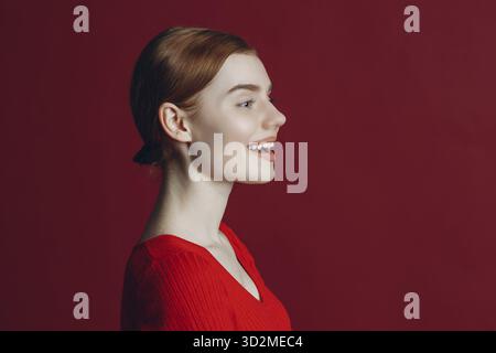 Portrait of young smile ginger woman profile portrait on red background Stock Photo
