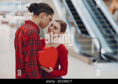 Beautiful happy young couple with shopping bags in shopping mall escalator Stock Photo