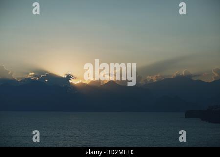 Dramatic sunset rays through cloudy dark sky over the ocean Stock Photo