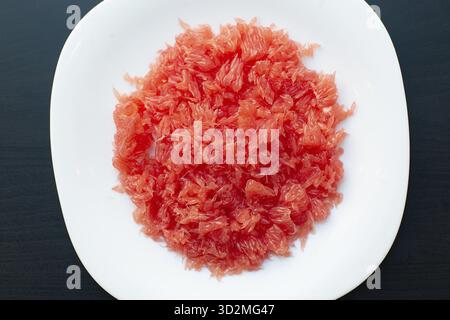 Red grapefruit fiber close-up. Fresh juicy cutted grapefruit without seeds and section shell on white plate Stock Photo