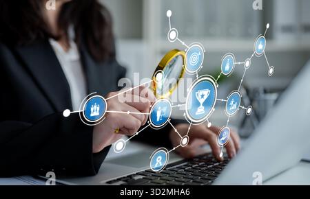 A business professional examines data with a magnifying glass, symbolizing analysis and insight in a modern workspace, showcasing productivity and con Stock Photo
