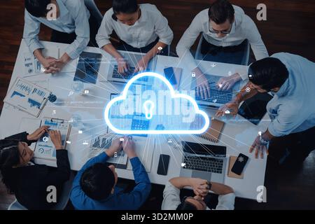 A diverse team collaborates on cloud security solutions within a modern office setting, utilizing laptops and engaging in innovative data sharing and Stock Photo