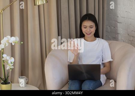 Portrait of asian woman enjoying using laptop at apartment interior indoor living room. Video call vlogger webinar stream concept Stock Photo