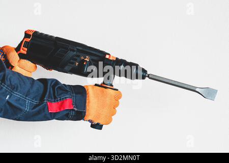workman with a rotary hammer. Hands in protective gloves with hammer drill perforator. Copy space. Stock Photo