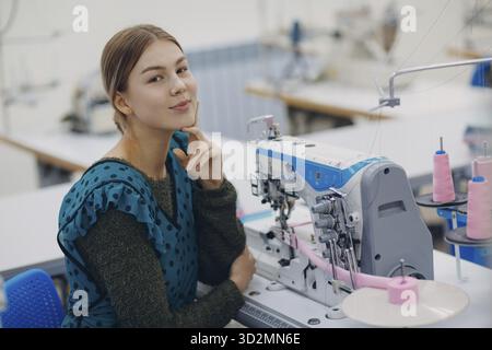 Young beautiful seamstress sews on sewing machine in factory Stock Photo