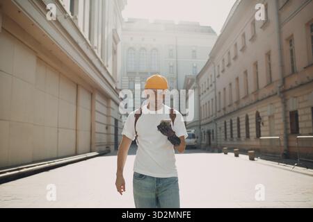Young disabled man tourist using mobile phone with artificial prosthetic hand and walking at sunny city street outdoor Stock Photo