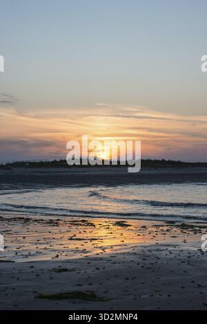 Sunset on a quiet beach with soft light on the waves, wet beach at low tide, dunes in the background, atmospheric, glowing, calm, warm atmosphere, ref Stock Photo