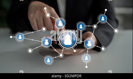 A business professional engages with a smartphone displaying a digital network of user profiles, highlighting modern connections in a professional wor Stock Photo