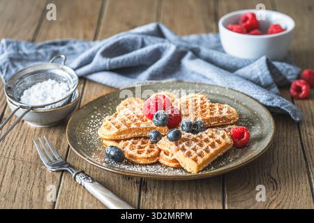 Homemade waffles with powdered sugar and berries on a wooden table Stock Photo